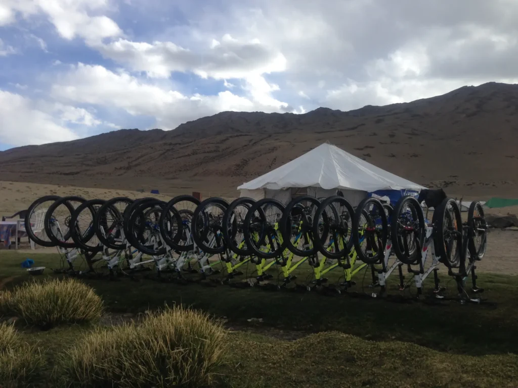 Row of mountain bikes lined up at Himalayan Nature Escapes' high-altitude expedition camp, tents and mountain ridgeline in the background